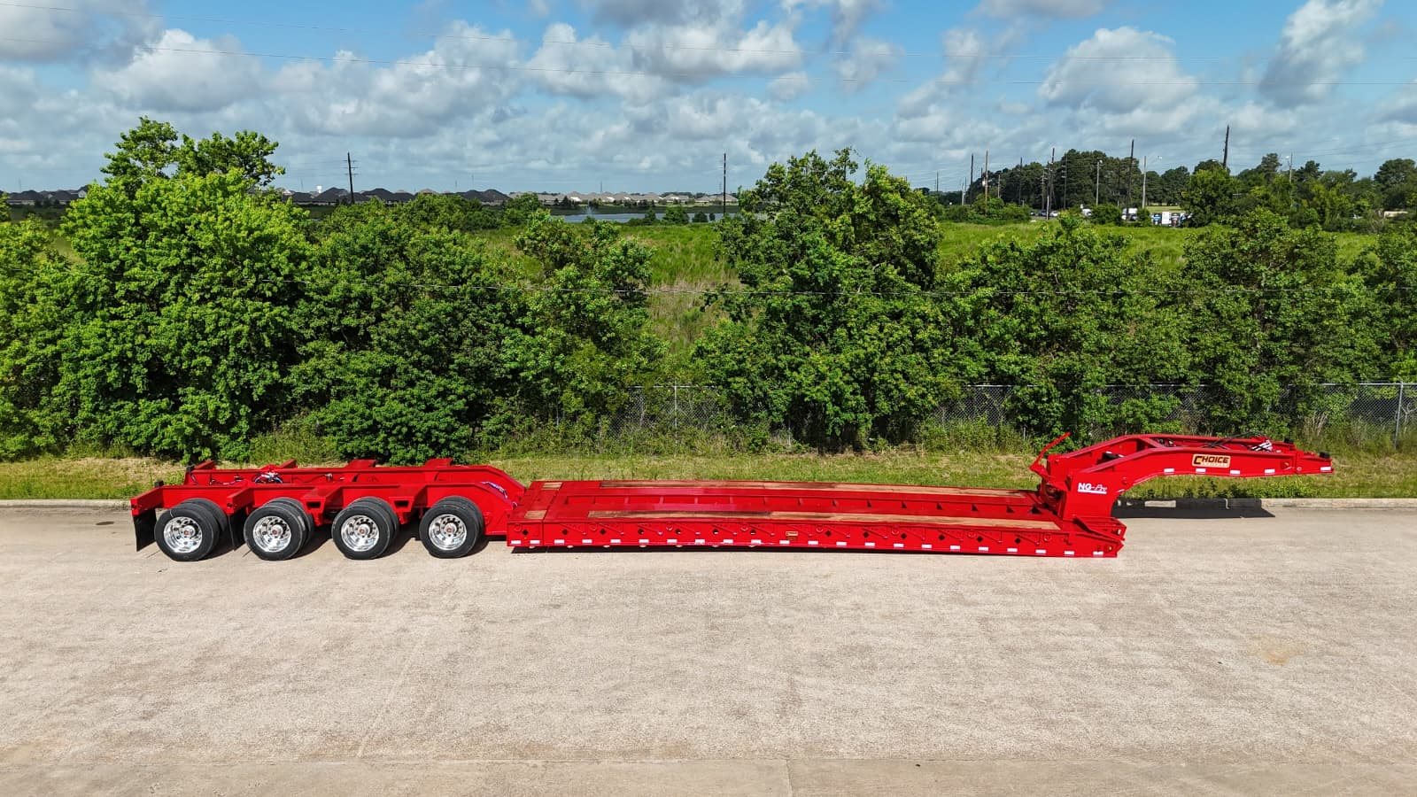 Full side profile of a red extendable lowboy trailer with Apitong deck inserts