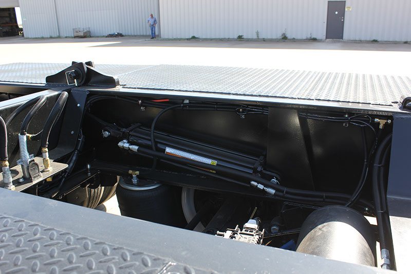 Hydraulic extension cylinder mounted beneath the rear deck of a lowboy trailer