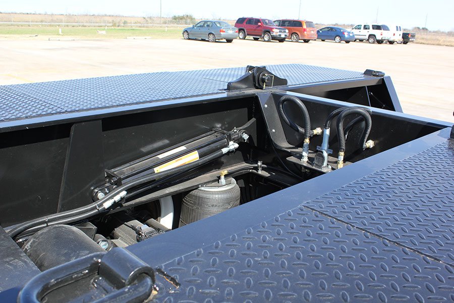 Twin hydraulic cylinders and air-ride bags under the rear deck of a lowboy